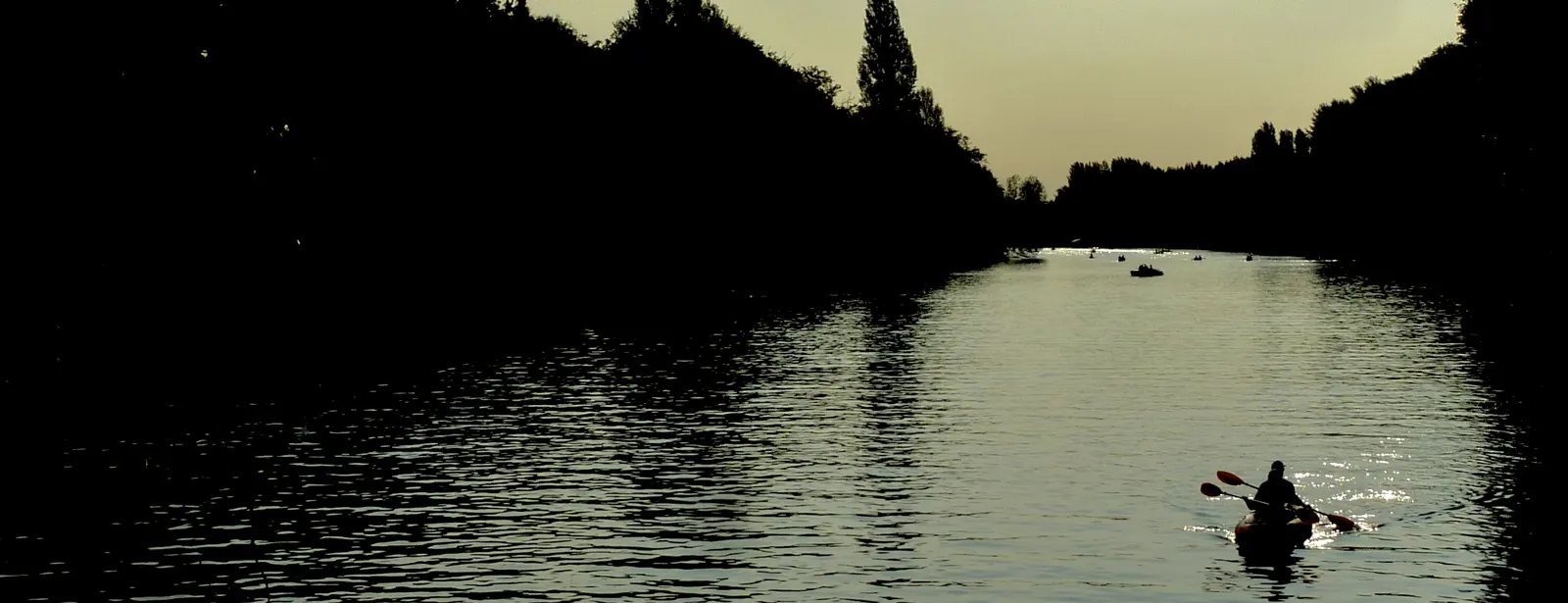Un kayak en silhouette sur le Cher au crépuscule, lumière dorée sur l’eau.